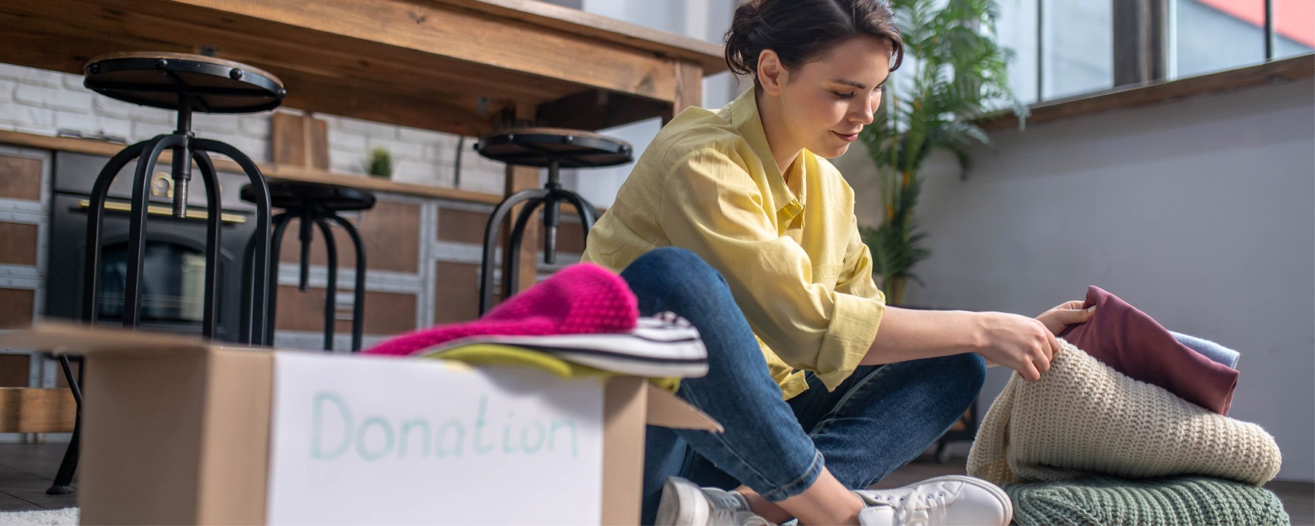 A homeowner packs up their bedroom for a move, sorting their clothes into boxes they want to keep, donate, and store.