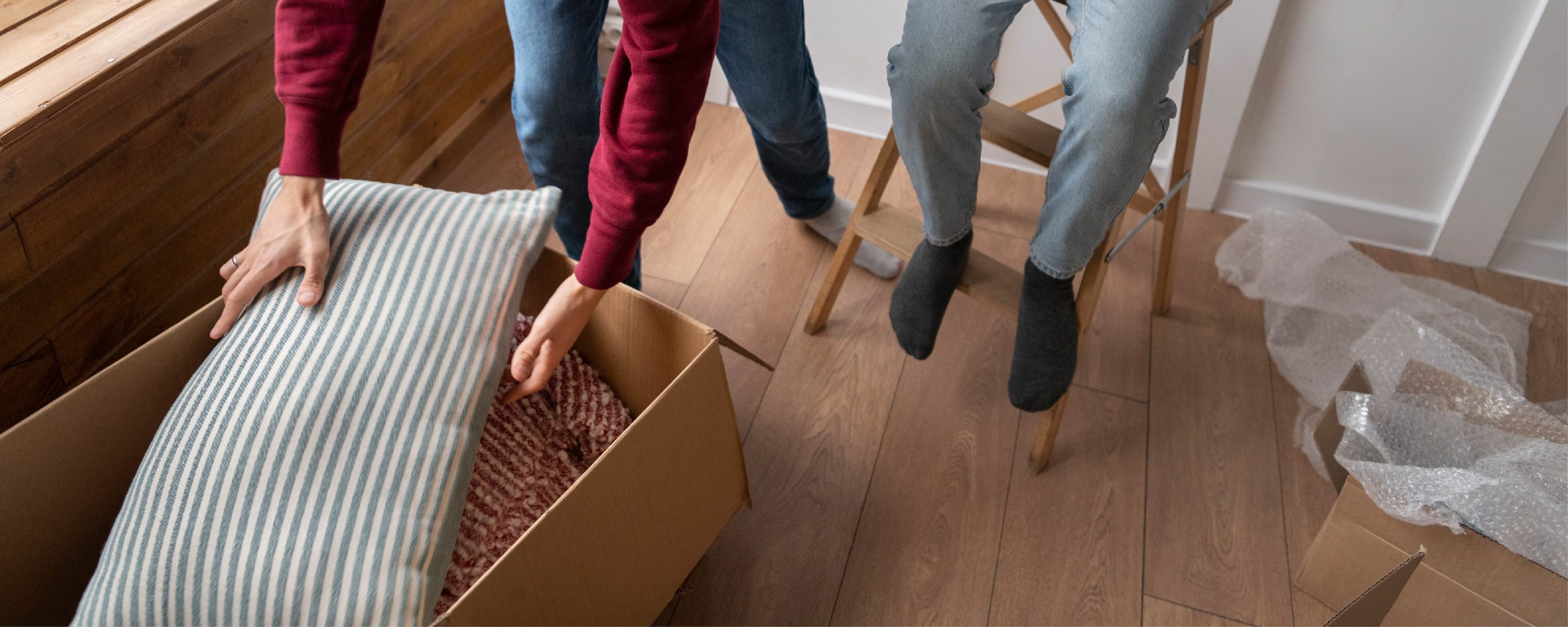 Bedroom linen and bedding are bundled up and packed into a box during a move.