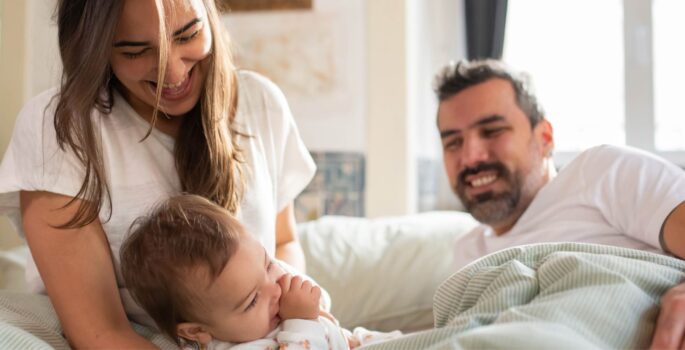 Parents hold their newborn baby in their small home