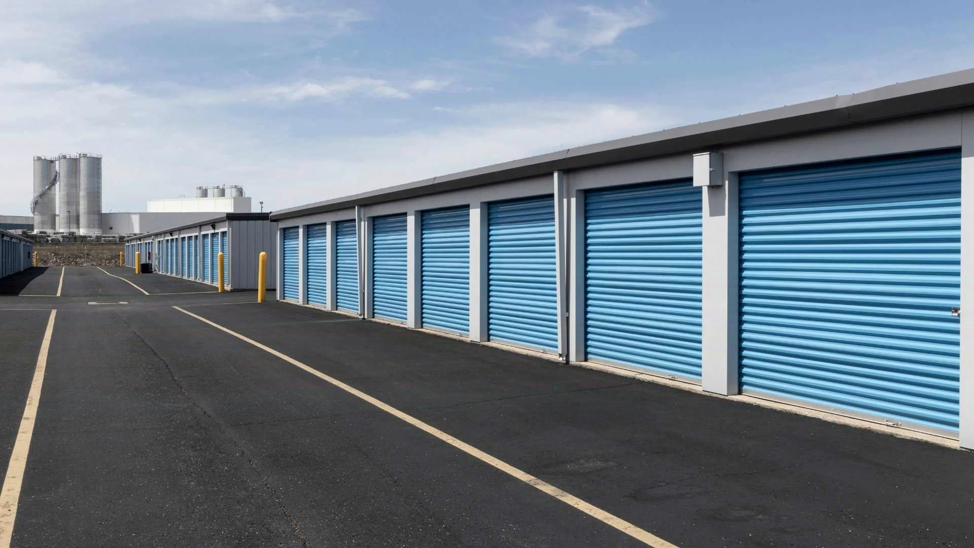 A row of blue roller-shutter drive-up storage units